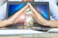 Protection of money from online transaction concept, with womanÃ¢â¬â¢s hands covering a jar of coins above a notebook Royalty Free Stock Photo